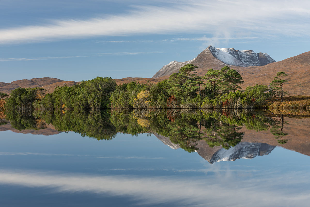 Photography workshops - mountain and native woodland reflected in a lake under blue sky with a band of white cloud