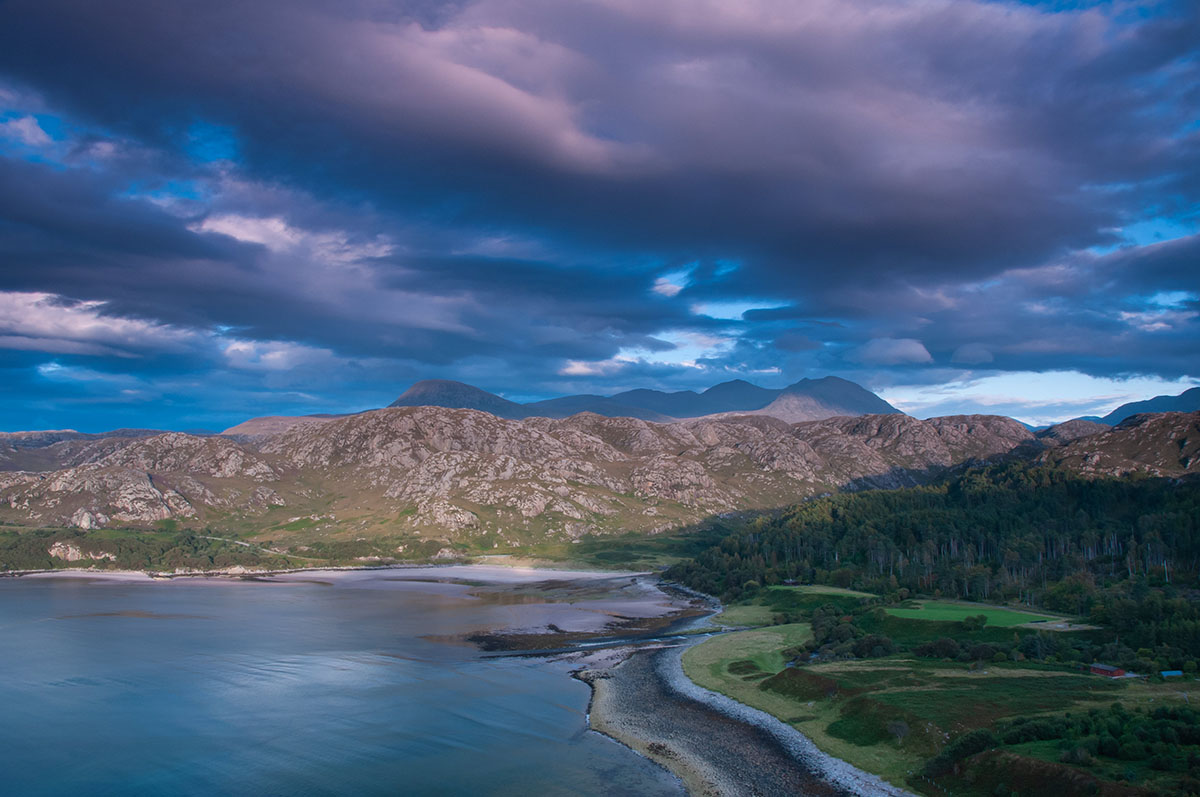 Torridon photography - purple clouds over a mountain, hills, a forest, a beach and a bay