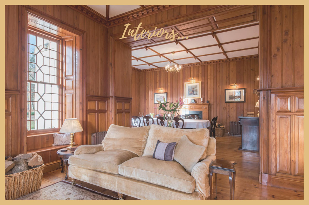 Commercial photograph showing the interior of a luxury exclusive use venue, featuring a couch in a wood panelled room