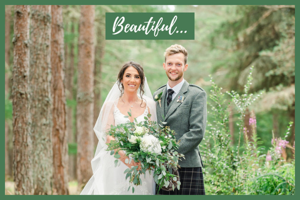 Caucasian bride and groom smiling and holding a bouquet and standing in woodland in front of trees and purple flowers