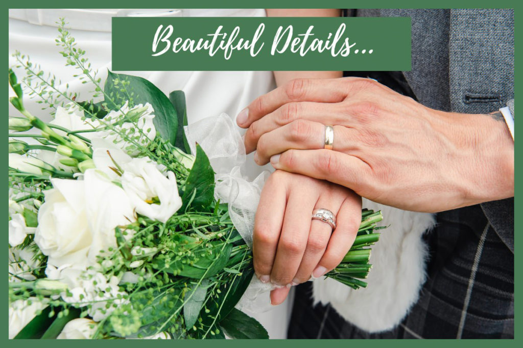 Close-up of a man's hand resting on a woman's hand, both wearing wedding rings, and with the woman's hand holding flowers