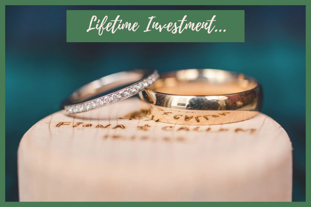 Gold and silver wedding rings on an engraved wooden box overlaid with lifetime investment text