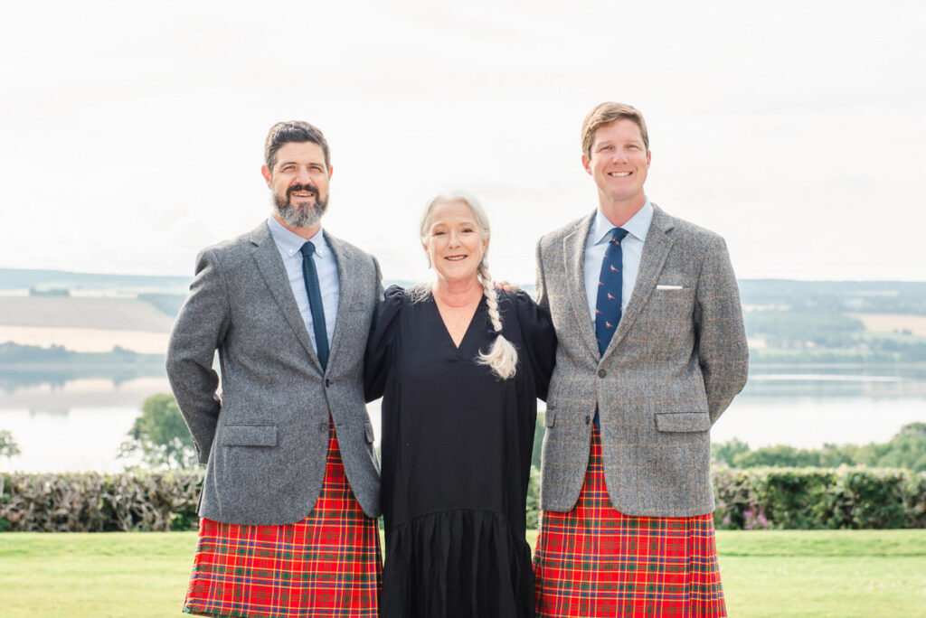 Brothers in grey jackets and red tartan kilts stand either side of their mother on a lawn during a Cromarty Family Photo Shoot