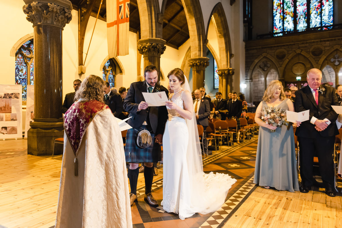 A wedding couple and congregation stand while singing at a Personalised Wedding Ceremony in Inverness Cathedral