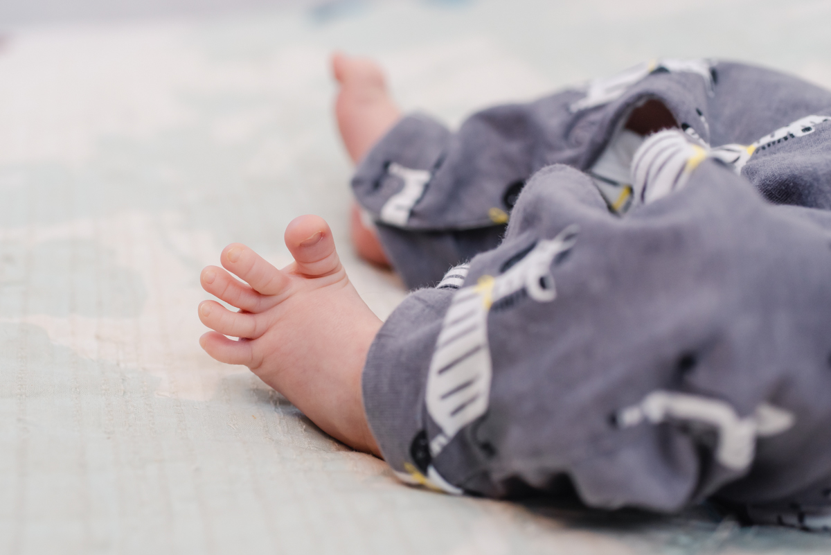 A close up of a newborn baby's feet dressed in a zebra patterned onesie