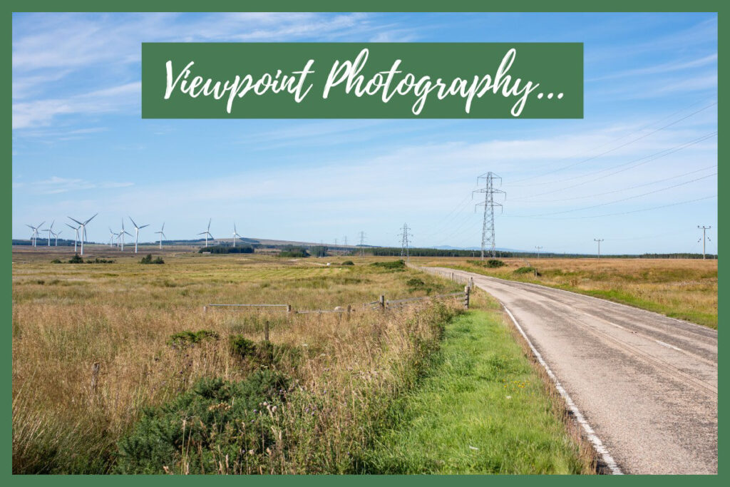 Promotional image for viewpoint photography showing a road beside an onshore wind farm, pylons and telegraph poles