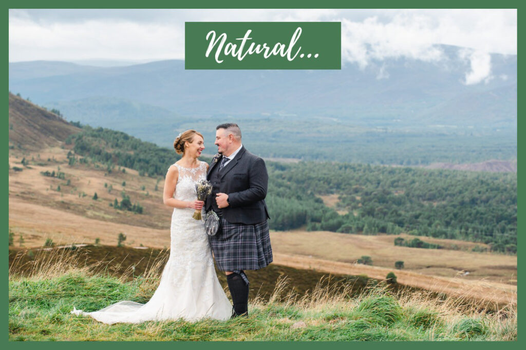 Bride in a white dress and groom in a kilt facing each other and smiling with hills and trees in the landscape beyond
